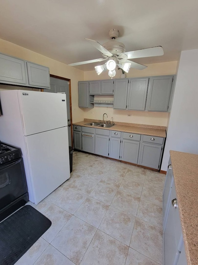 kitchen featuring ceiling fan, white refrigerator, light tile patterned flooring, sink, and black range