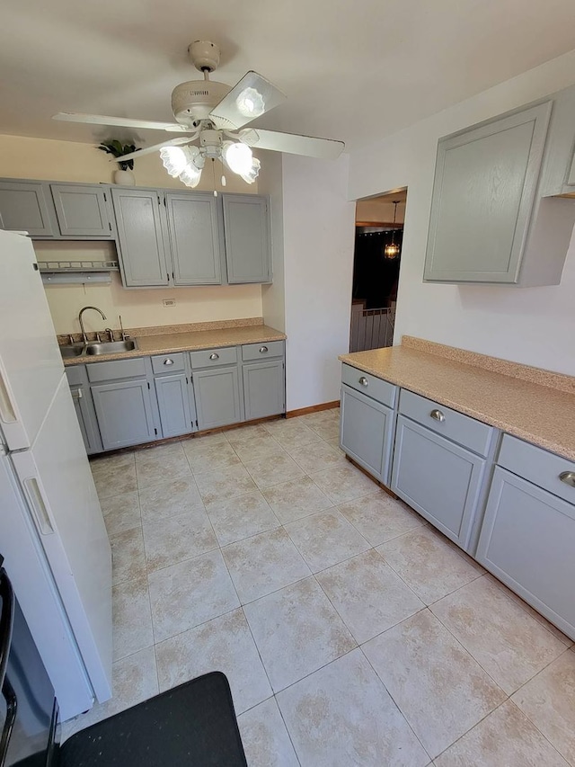 kitchen with gray cabinetry, light tile patterned flooring, sink, and ceiling fan