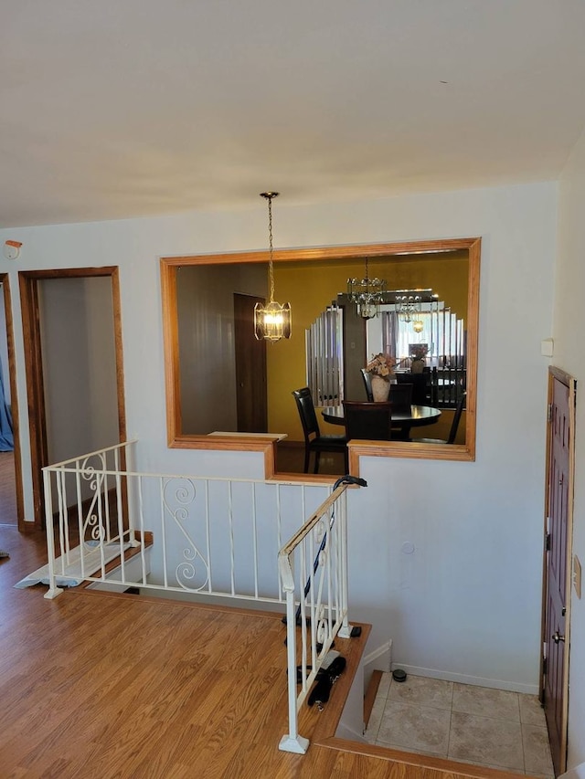 staircase featuring wood-type flooring and a notable chandelier