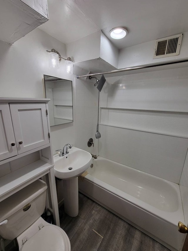 bathroom featuring wood-type flooring, shower / tub combination, and toilet