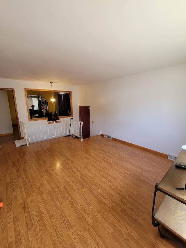 unfurnished living room featuring light hardwood / wood-style floors and an inviting chandelier