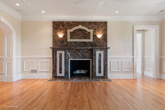 unfurnished living room with ornamental molding, wood-type flooring, ceiling fan, and a fireplace