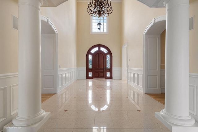 344 Old Sutton Rd, Barrington, IL 60010 - tiled entrance foyer featuring decorative columns, a decorative wall, a chandelier, a wainscoted wall, and arched walkways