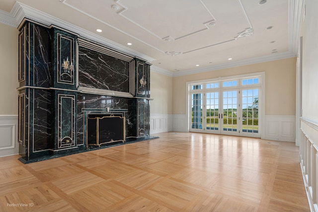 unfurnished living room with ornamental molding, a premium fireplace, light parquet floors, and french doors