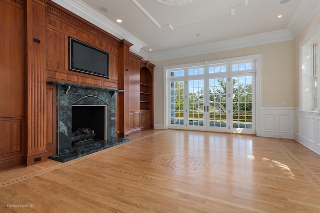 unfurnished living room featuring light hardwood / wood-style floors, ornamental molding, a high end fireplace, and french doors