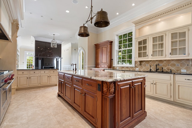 kitchen with stainless steel stove, a kitchen island with sink, and cream cabinetry