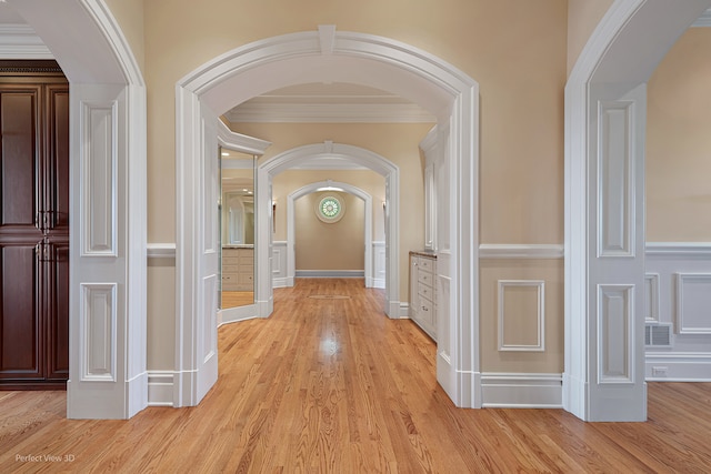 hall with light wood-type flooring and ornamental molding