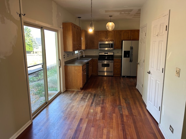 kitchen with appliances with stainless steel finishes, dark hardwood / wood-style floors, pendant lighting, and sink