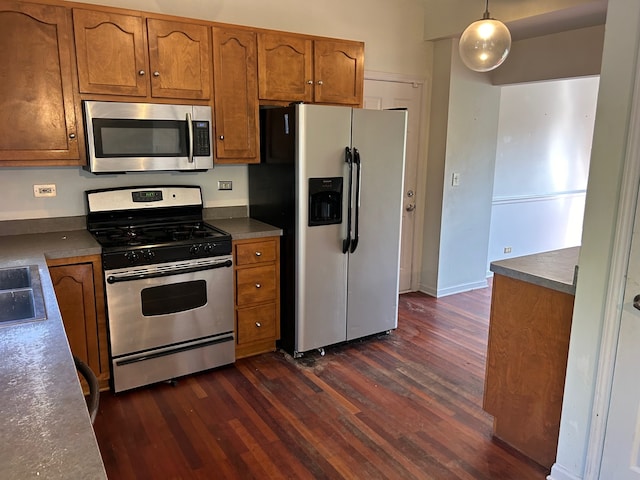 kitchen featuring pendant lighting, appliances with stainless steel finishes, and dark hardwood / wood-style floors