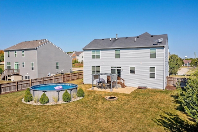 back of property featuring a fenced in pool, a yard, and a fire pit