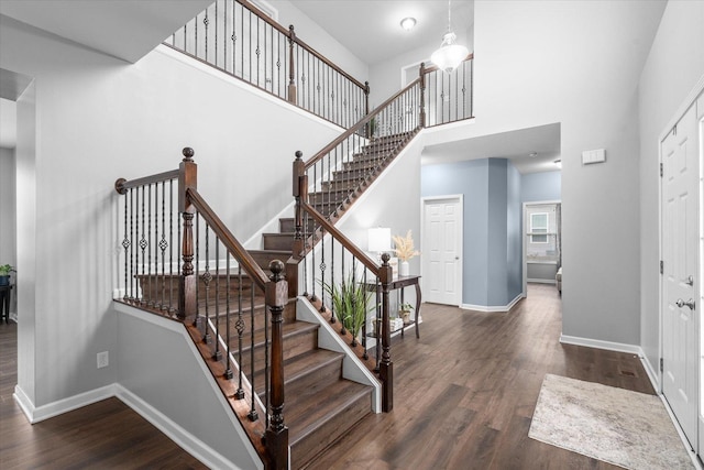 staircase with hardwood / wood-style flooring and a towering ceiling