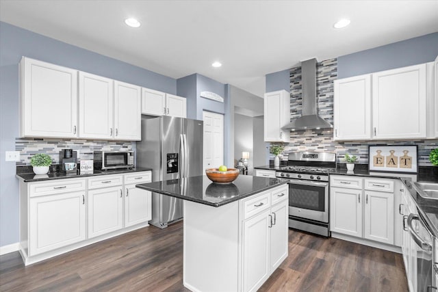 kitchen featuring wall chimney exhaust hood, stainless steel appliances, a center island, and white cabinets