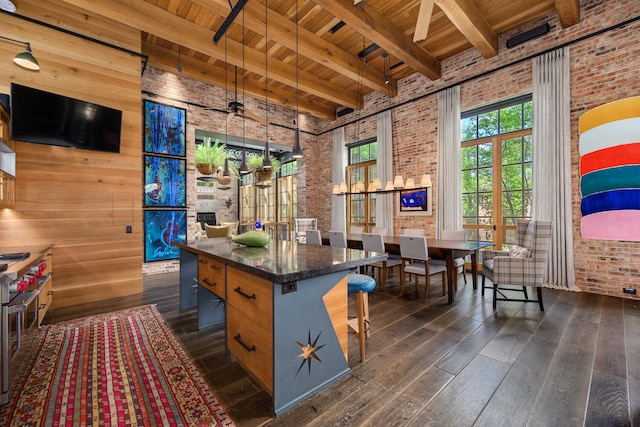 kitchen with dark hardwood / wood-style floors, a breakfast bar area, ceiling fan, and brick wall