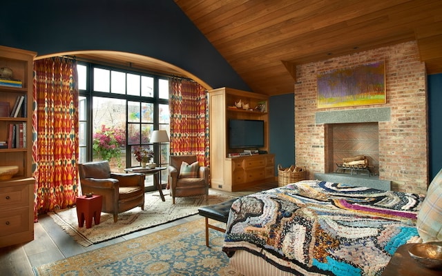 bedroom featuring vaulted ceiling, light hardwood / wood-style floors, brick wall, and wooden ceiling