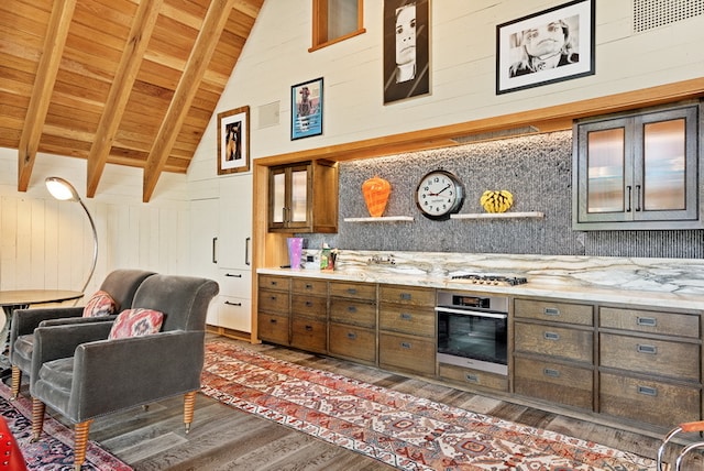 kitchen with dark wood-type flooring, beam ceiling, wood walls, high vaulted ceiling, and appliances with stainless steel finishes