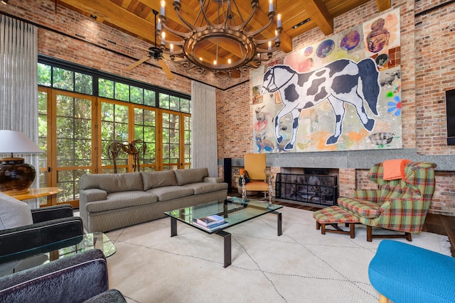 living room featuring beamed ceiling, wood ceiling, brick wall, a high ceiling, and ceiling fan with notable chandelier