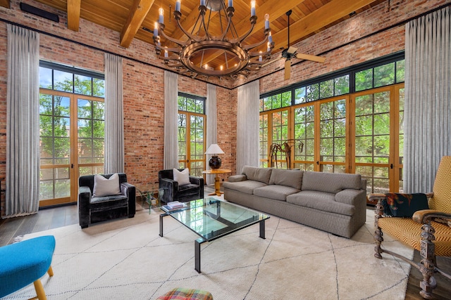 living room featuring ceiling fan with notable chandelier, beamed ceiling, wooden ceiling, a high ceiling, and hardwood / wood-style floors