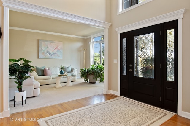 foyer entrance with wood-type flooring and crown molding