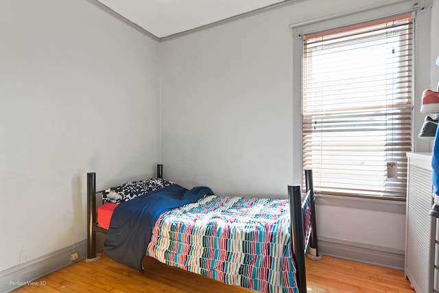 bedroom with light wood-type flooring and crown molding