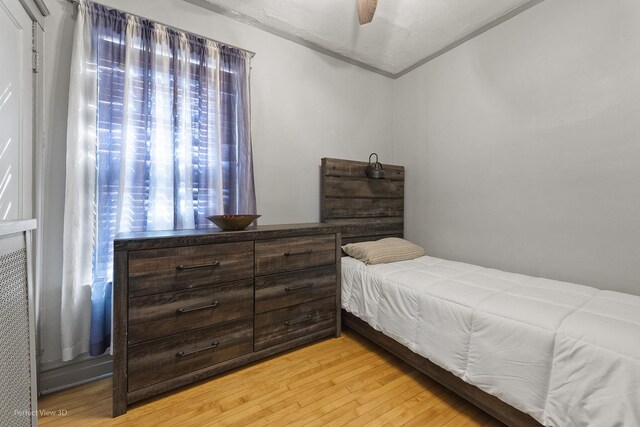 bedroom with a textured ceiling, ceiling fan, and light hardwood / wood-style flooring