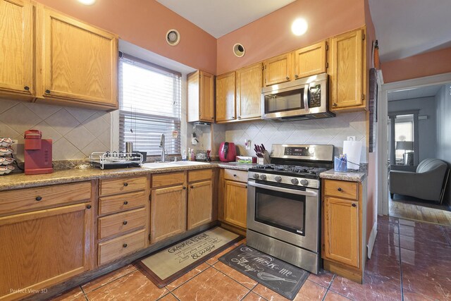 kitchen with dark tile patterned flooring, appliances with stainless steel finishes, sink, and tasteful backsplash