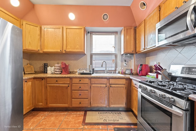 kitchen featuring sink, lofted ceiling, backsplash, appliances with stainless steel finishes, and light tile patterned floors