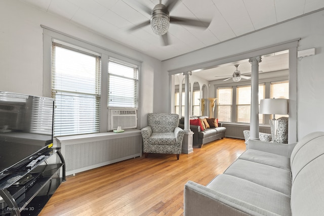 living room with light wood-type flooring, cooling unit, radiator heating unit, and ceiling fan