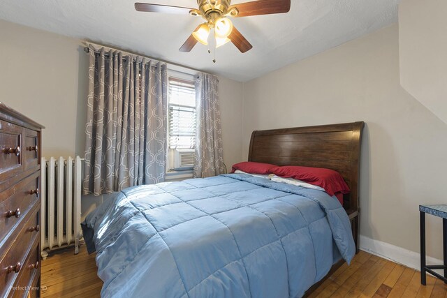 bedroom with wood-type flooring, radiator heating unit, and ceiling fan