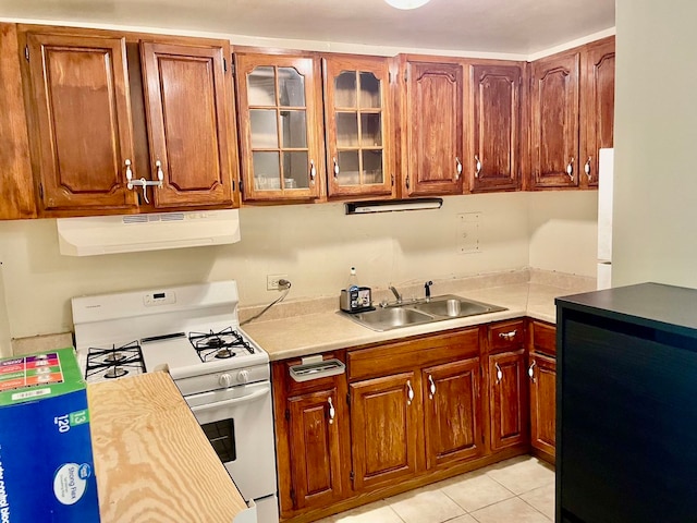 kitchen with white range with gas stovetop, light tile patterned flooring, sink, and ventilation hood