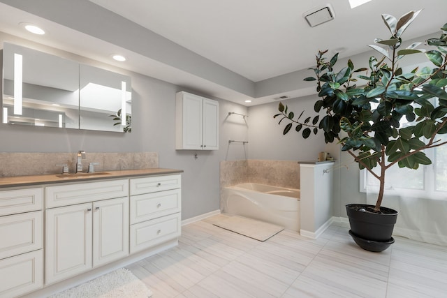 bathroom featuring vanity, a washtub, and tile patterned floors