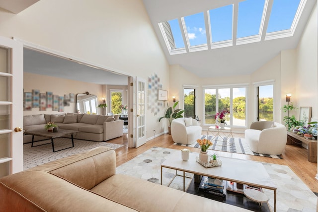 living room with high vaulted ceiling, light hardwood / wood-style floors, and a skylight