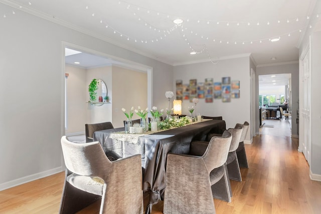 dining area with ornamental molding and light hardwood / wood-style floors