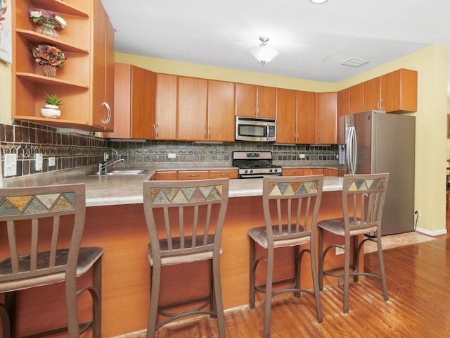 kitchen with stainless steel appliances, light hardwood / wood-style floors, kitchen peninsula, and a breakfast bar area