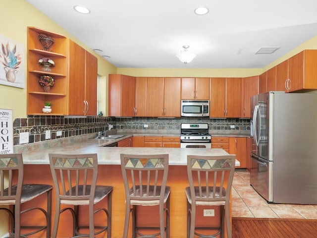 kitchen with appliances with stainless steel finishes, kitchen peninsula, sink, and a kitchen bar