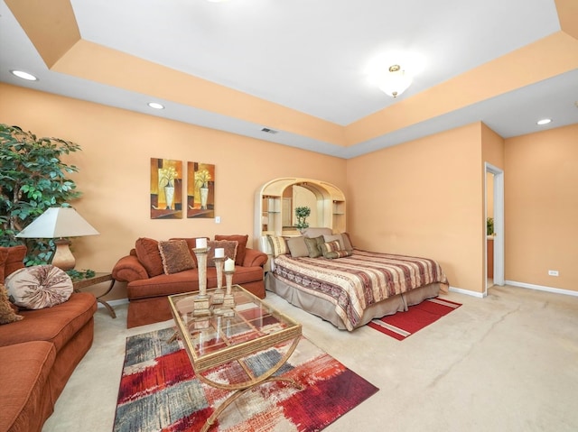 carpeted bedroom with a raised ceiling