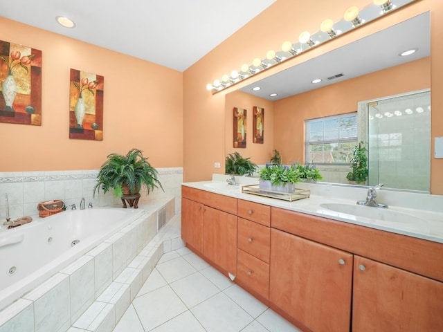 bathroom with a relaxing tiled tub, vanity, and tile patterned flooring