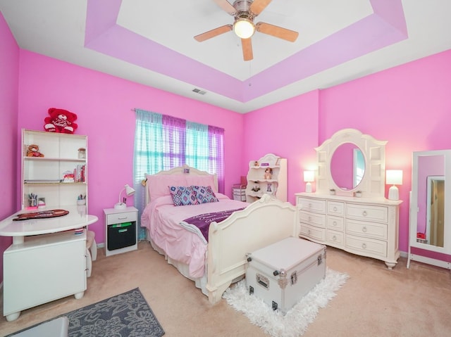 carpeted bedroom featuring a raised ceiling and ceiling fan