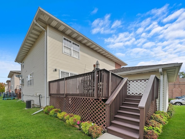 rear view of house with a lawn, a deck, and central AC unit