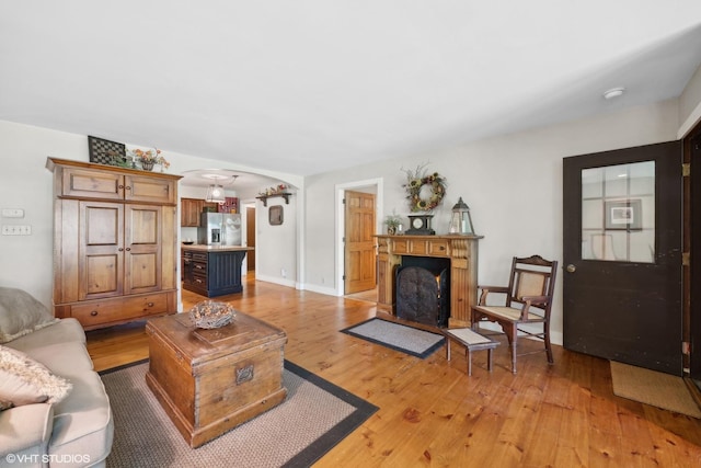 33 E Maple Ave, Cortland, IL 60112 - living room with arched walkways, light wood-style flooring, a fireplace with flush hearth, and baseboards