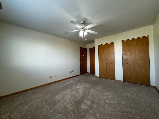 unfurnished bedroom featuring ceiling fan, two closets, and carpet