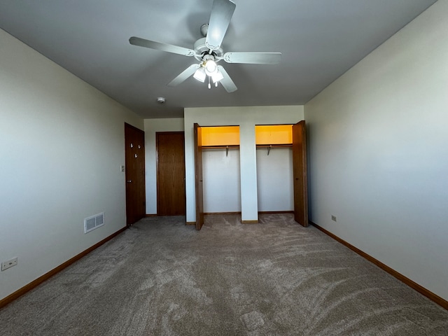 unfurnished bedroom featuring carpet, ceiling fan, and multiple closets