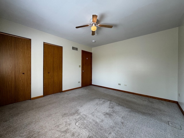 unfurnished bedroom featuring carpet, two closets, and ceiling fan