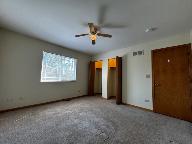 unfurnished bedroom with carpet flooring, ceiling fan, and multiple closets