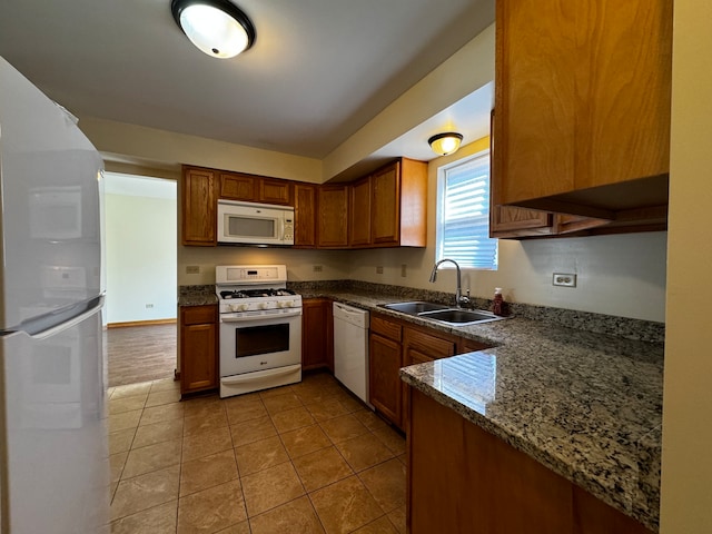 kitchen featuring light tile patterned flooring, sink, kitchen peninsula, white appliances, and dark stone countertops