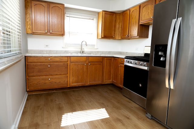 kitchen with appliances with stainless steel finishes, sink, and light wood-type flooring