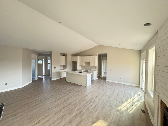 unfurnished living room with wood-type flooring and vaulted ceiling