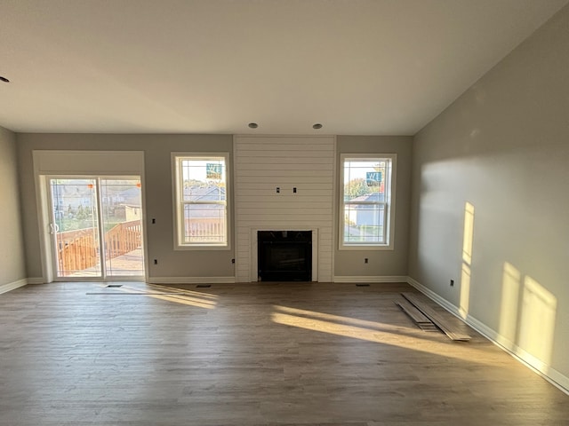 unfurnished living room with lofted ceiling, wood-type flooring, a fireplace, and a wealth of natural light