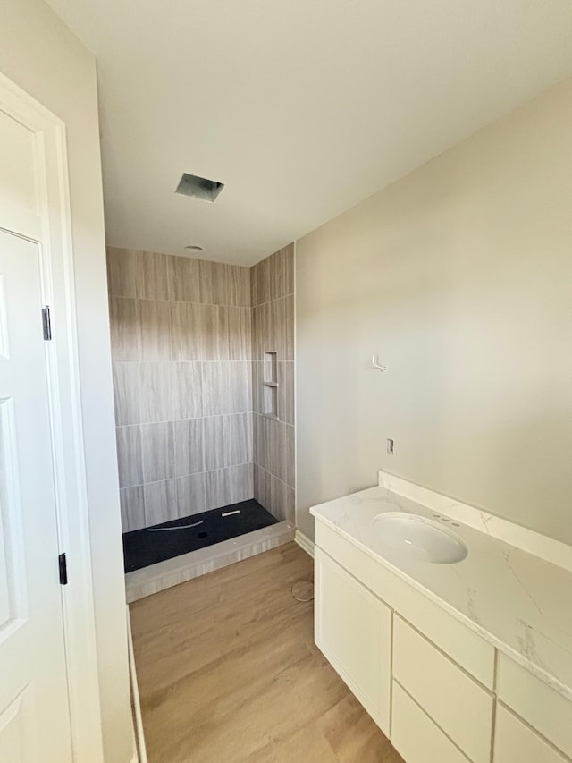 bathroom with wood-type flooring, vanity, and walk in shower