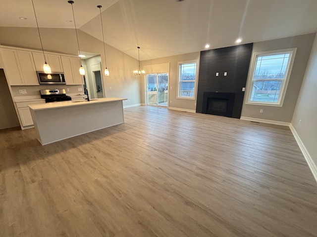 kitchen featuring light hardwood / wood-style floors, white cabinets, hanging light fixtures, and appliances with stainless steel finishes