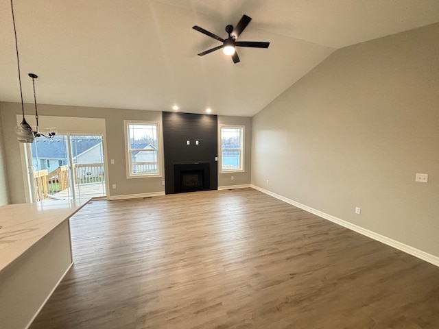 unfurnished living room featuring a fireplace, ceiling fan with notable chandelier, dark wood-type flooring, and vaulted ceiling